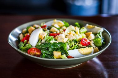 Sezar salatası, ızgara tavuk göğsü, kızarmış ekmek, haşlanmış yumurta ve vişneli domates.