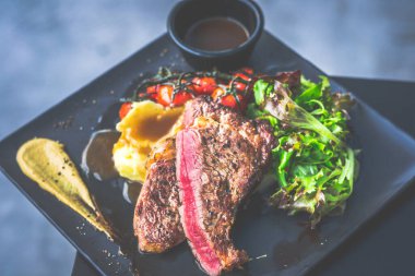 NZ pirzola bifteği, tavada az pişmiş, yanında gerçek köy kremalı patates püresi, sarmaşıklı vişneli domates, salata.