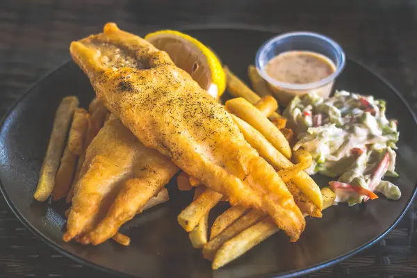 Patates kızartması, lahana salatası ve tartar sosuyla servis edilen beyaz balık ve patates kızartması.