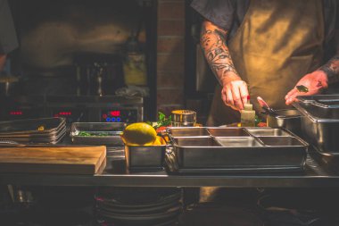 Singapur 'da açık bir mutfakta çalışan dövmeli bir aşçı.