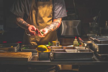 Singapur 'da açık bir mutfakta çalışan dövmeli bir aşçı.