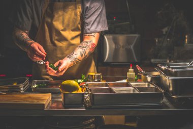 Singapur 'da açık bir mutfakta çalışan dövmeli bir aşçı.