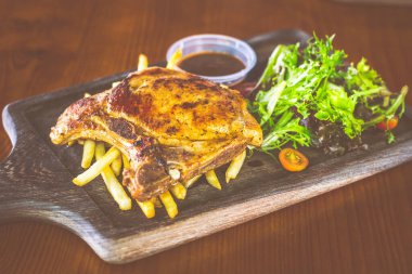 Yanında salata ve sos olan Cajun Rosemary Pork Chop.