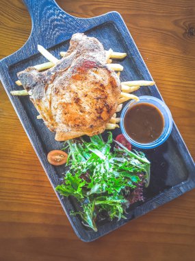 Yanında salata ve sos olan Cajun Rosemary Pork Chop.