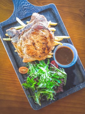 Yanında salata ve sos olan Cajun Rosemary Pork Chop.