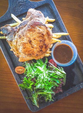 Yanında salata ve sos olan Cajun Rosemary Pork Chop.