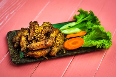 Çiğ havuç ve marulla servis edilen Tayland usulü kızarmış tavuk kanadı.