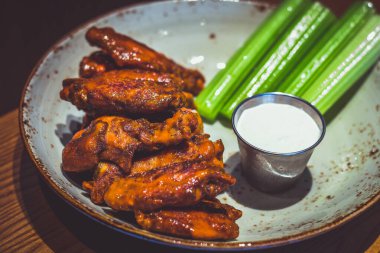 Klasik Bufalo sosuyla birlikte yavaşça kızartılmış kanatlar. Kereviz ve mavi peynir sosuyla servis edilir.