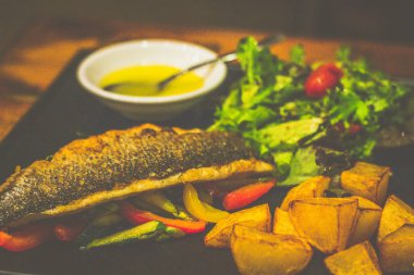 Gri İtalyan deniz ürünleri sotelenmiş sebze ve kızarmış patatesle servis edilir.