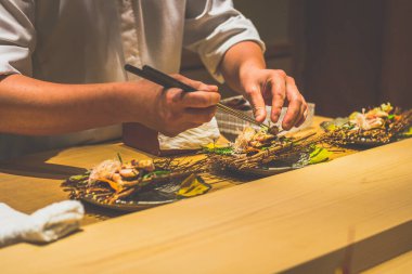 Japon bir aşçının elleri bir kaiseki omakase restoranında yemek hazırlıyor.