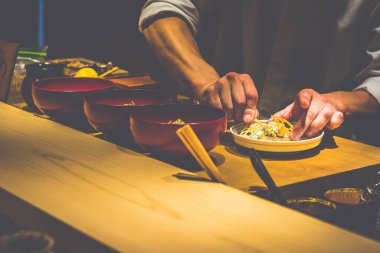 Japon bir aşçının elleri bir kaiseki omakase restoranında yemek hazırlıyor.