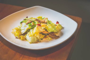 Lahanayla kızartılmış lahana, domuz göbeği, beyaz tabakta servis edilen kurutulmuş kırmızı biber.