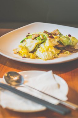 Lahanayla kızartılmış lahana, domuz göbeği, beyaz tabakta servis edilen kurutulmuş kırmızı biber.