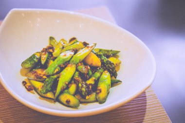 Kızarmış kuşkonmaz ve soslu beyaz bir tabakta servis ediliyor.