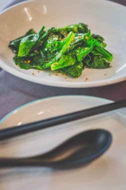 Beyaz bir tabakta servis edilen kıymalı sarımsaklı kailan.