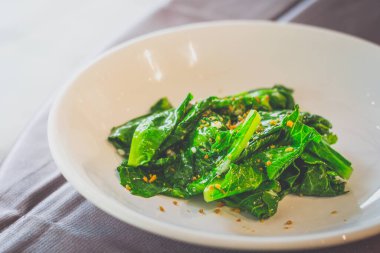 Beyaz bir tabakta servis edilen kıymalı sarımsaklı kailan.