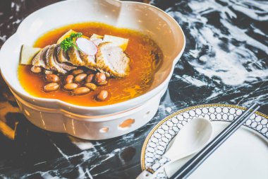 Tofu dilimleri ve beyaz bir tabakta haşlanmış fıstıkla pişirilmiş ördek.