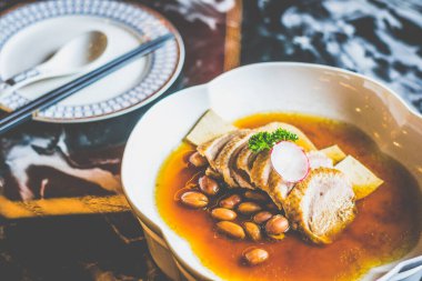 Tofu dilimleri ve beyaz bir tabakta haşlanmış fıstıkla pişirilmiş ördek.