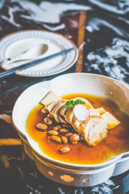 Tofu dilimleri ve beyaz bir tabakta haşlanmış fıstıkla pişirilmiş ördek.