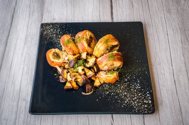 Siyah tabakta servis edilen sotelenmiş mantarlı tavuk roulade.