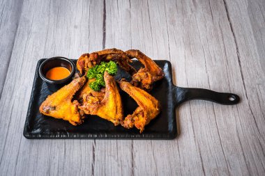 Kızarmış tavuk kanadı ve yanında sos tabağında servis edilen aperatif parmak yemeği.