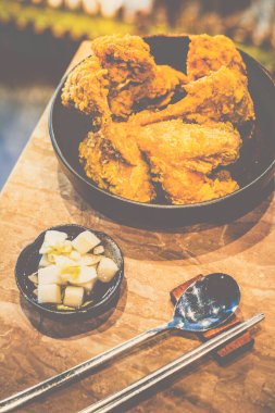 Kore usulü kızarmış tavuk kanatları masanın üstünde üst üste yığılmış.