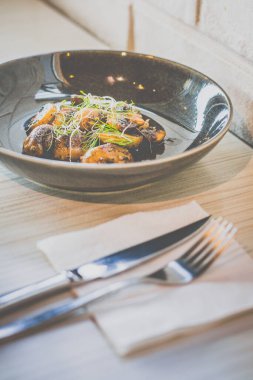 Siyah bir tabakta servis edilen tereyağlı ve otlu sotelenmiş mantar.