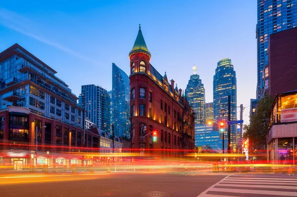 Stock image Canada, Toronto. The famous Gooderham building and the skyscrapers in the background. View of the city in the evening. Blurring traffic lights. Modern and ancient architecture. Night city.