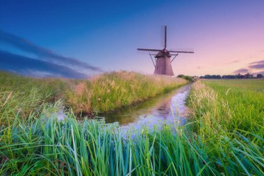 Hollanda 'daki yel değirmenleri. Tarihi binalar. Tarım. Gün batımında yaz manzarası. Parlak gökyüzü ve rüzgar gülü. Tasarım fotoğrafçılığı.