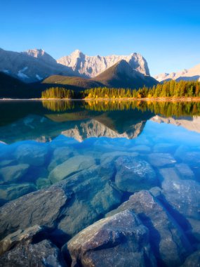 Mountain landscape at the day time. Lake and forest in a mountain valley. Natural landscape with a blue sky. Reflections on the surface of the lake.