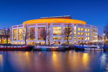 Amsterdam, Hollanda. Opera ve Bale Binası. Akşam manzarası. Mavi gökyüzü ve şehir ışıkları. Hollanda kanalları. Suyun yüzeyindeki yansımalar. Tasarım ve duvar kağıdı fotoğrafçılığı.
