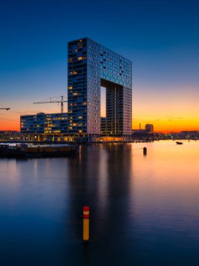 Amsterdam, Netherlands. A cityscape in the evening. A skyscraper and business center near the water in the bay. Architecture of the Netherlands. Travel photography.