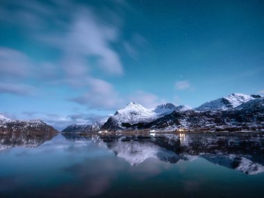 Norveç, Lofoten Adası. Geceleri dağları ve sudaki yansımaları. Kış manzarası. Yıldızlı gökyüzü ve Aurora Borealis. Arka plan olarak doğa. Kuzey yolculuğu.