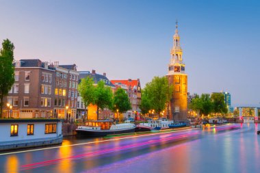 Montelbaan Kulesi, Amsterdam, Hollanda. Akşam manzarası. Karanlık gökyüzü ve şehrin ışıkları. Hollanda kanalları. Suyun yüzeyindeki yansımalar. Tasarım ve duvar kağıdı fotoğrafçılığı.