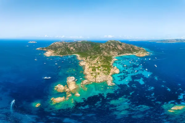 An island in the middle of the sea. Drone view of a yachts, boats and island. Vacationing people. Vacation and holidays. Summer time for sea travel. The sea bay.