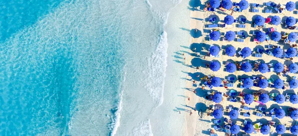Aerial view on beach, people and umbrellas. Vacation and adventure. Mediterranean Sea. Top view from drone at beach and azure sea. View on the coast from drone.