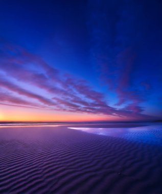 Güneş doğarken deniz manzarası. Uzun pozlama. Gökyüzünde parlak bulutlar. Deniz kıyısındaki kum hatları. Gün batımında parlak gökyüzü. Dalgalar alçaldığında kumlu bir sahil. Duvar kağıdı ve arkaplan.