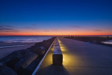 Ostend, Belçika. Gün batımında iskele manzarası. Deniz kenarında yürümek için bir yer. Uzun pozlama. Kıyı manzarası.
