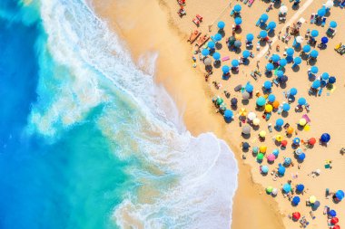 Aerial view on the beach, people and umbrellas. Vacation and adventure. Beach and blue water. Top view from drone at beach and azure sea. View on the coast from drone.