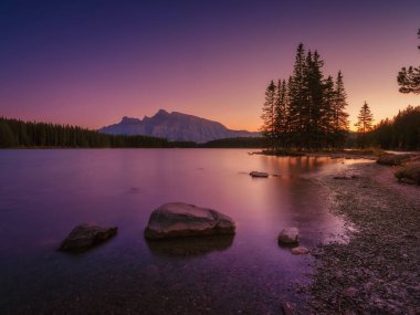 İki Jack Gölü, Banff Ulusal Parkı, Alberta, Kanada. Şafak vakti dağ manzarası. Vadideki güneş ışınları. Gün doğarken bir dağ vadisinde göl ve orman. Parlak güneş ışığıyla doğal manzara. 