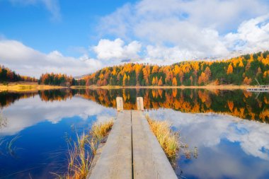 Gölün yüzeyinde yansımalar ve küçük bir köprü. İsviçre 'de sonbahar manzarası. Bulutlar ve düşen orman. Mavi dağ gölü. Arkaplan, duvar kağıdı, kartpostallar için fotoğraf.