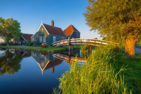 Zaanse Schans, Hollanda. Gün batımında Hollanda 'da tarihi bir yer. Kanaldaki yansımalar. Eski bir peynir fabrikasının mağazası ve inşaatı. Arkaplan, duvar kağıdı, kartpostallar için fotoğraf.