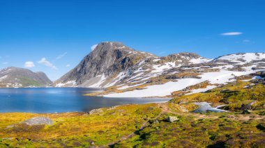 Norveç. Dağ manzarası. Vadideki yüksek bir dağın manzarası. Kocaman keskin kayalar ve su yüzeyinde yansıma. Yaz mevsiminde manzara. Yürüyüş için bir yer.