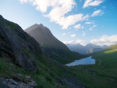 Norveç 'te doğa. Vahşi Norveç 'in panoramik manzarası. Kayaların ve dağların arasındaki göl. Gün batımında parlak güneş ışığı. Tatil ve seyahatler Kuzey 'de. 