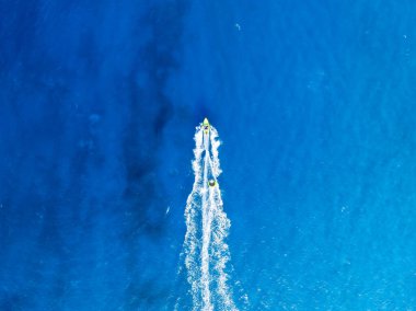 Tatil ve boş zaman. Motorlu deniz manzaralı. Güneşli bir günde mavi denizde hızlı teknenin hava manzarası. Deniz yüzeyinde hızlı gemi. Drone 'dan deniz pelerini. Arkaplan, duvar kağıdı, kartpostal.