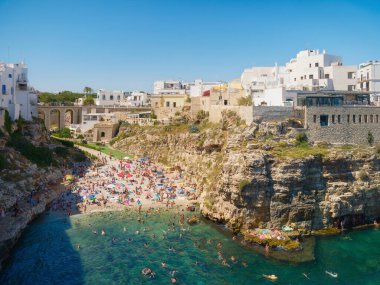 Polignano a Mare, İtalya. Kayaların arasındaki sahil. Köyün manzarası. Deniz kıyısındaki uçurumun kenarındaki eski binalar. İtalyan mimarisi. Arka planlar, duvar kağıtları, kartpostallar için fotoğraflar.
