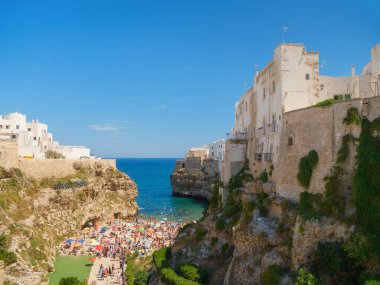 Polignano a Mare, İtalya. Kayaların arasındaki sahil. Köyün manzarası. Deniz kıyısındaki uçurumun kenarındaki eski binalar. İtalyan mimarisi. Arka planlar, duvar kağıtları, kartpostallar için fotoğraflar.