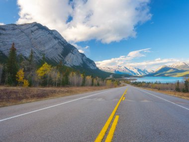 Asfalt yolu. Ufuktaki yüksek dağlar. Seyahat yönü. Tatil ve arabayla seyahat. Duvar kağıdı, arka plan, kartpostal. Doğa ve altyapı.