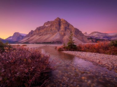 Bow Gölü, Alberta, Kanada. Gün doğumunda dağ manzarası. Suyun yüzeyindeki yansımalar. Vadideki güneş ışınları. Arkaplan, duvar kağıdı, kartpostallar.