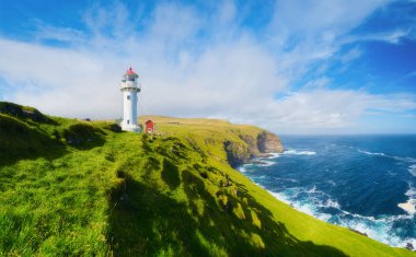 Akraberg Deniz Feneri, Suduroy Adası, Faroe Adaları, Danimarka. Kayaların, tarlanın ve okyanusun panoramik manzarası. Dağın tepesindeki deniz feneri. Seyahat için güzel bir yer. Arkaplan, duvar kağıdı, kartpostallar.